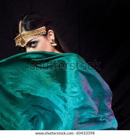 young beautiful oriental style woman covering herself with a green veil