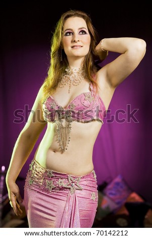 young beautiful woman in a pink oriental dress dancing the belly dance
