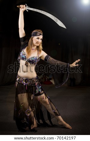 oriental woman dancing the typical belly dancing with a sabre