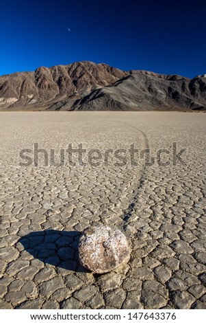 mysterious phenomenon where several rocks glide on their own and sometimes change direction on flat clay like desert floor and leave tracks for hundreds of feet racetrack in Death valley national park