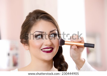 Beautiful woman doing make-up on face with cosmetic brush
