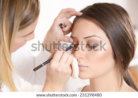 Professional Make-up artist doing beatiful girl makeup in studio