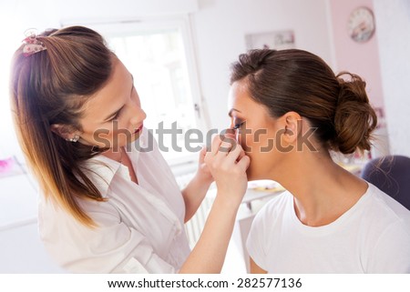 Professional Make-up artist doing beautiful girl makeup in studio and using artificial eyelashes