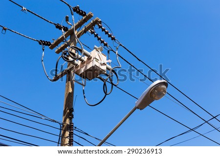 A power utility pole with transformers and street light.
