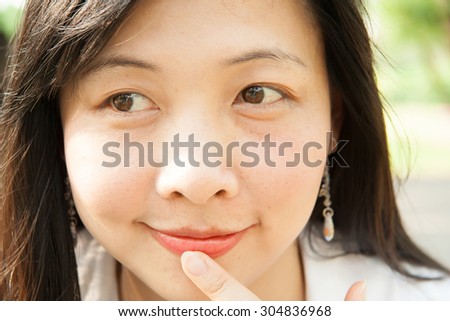 Woman with finger on lip, eyes looking to her right