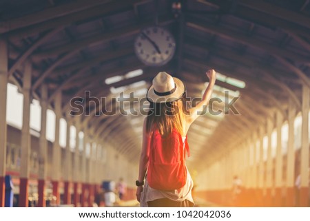 Beautiful young asian woman traveler looking clock over head with red bag ,Waiting for train at train station, Travel and vacation concept.