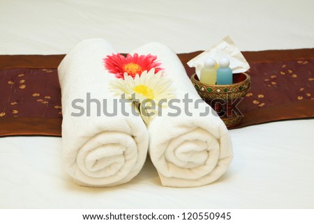 bath towels rolled with flower on bed