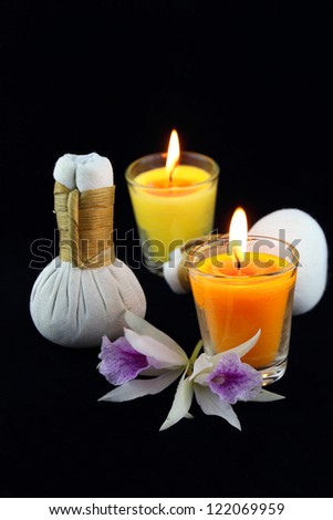 herbal compress balls for spa treatment with candles and white orchid flowers