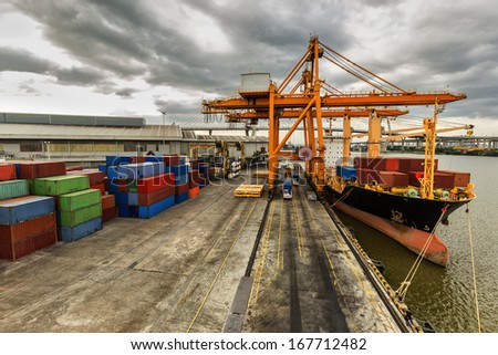 Industrial Container Cargo Freight Ship With Working Crane Bridge In Shipyard With Truck Top View