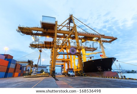 Industrial Container Cargo freight ship with working crane bridge in shipyard with truck Industrial Container Cargo freight ship with working crane bridge in shipyard with truck
