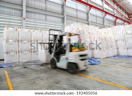 worker driving a forklift loader in warehouse with load jumbo bag