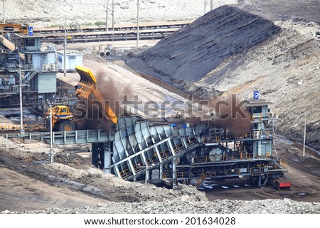 heavy construction tipper trucks dump coal to the conveyor at coal mine
