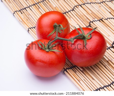 Bunch of fresh tomatoes with water drops on bamboo mat. Top view.