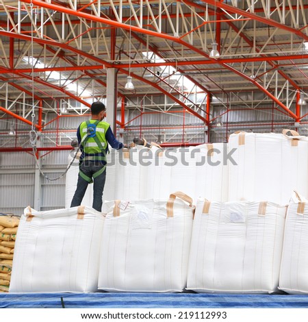 Warehouse worker wearing safety harness and safety line working on big bag stack