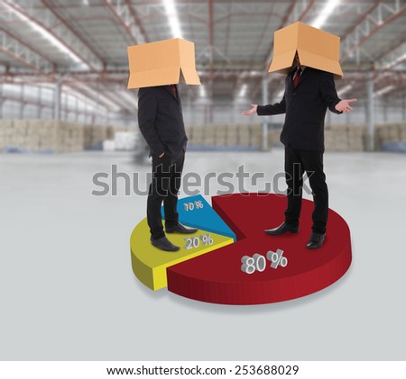 Unrecognizable businessman in suit wearing carton box on head talking on circle graph at large warehouse