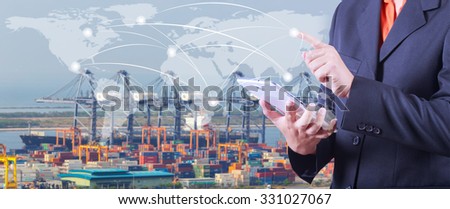 hand presses on world map with digital tablet,Industrial Container Cargo freight ship  at dusk for Logistic Import Export background (Elements of this image furnished by NASA)