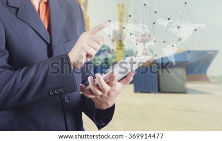 Businessman hand working and smart phone and laptop on Industrial Container Cargo freight ship background (Elements of this image furnished by NASA)