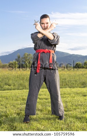 Woman ninja in an aggressive posture  with shuriken