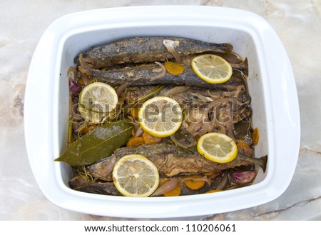 Grilled young Mediterranean mackerel marinade in ceramic plate, decorated with organic lemon slices and laurel