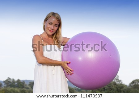 Cute young woman playing outdoors with pink fit-medicine ball