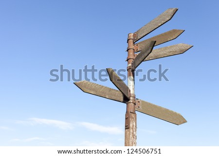Old wooden direction signs against blue sky