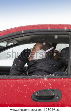 Cute girl with flu symptoms sneezes in a car on snowy  winter day. Using handkerchief closes mouth with her hands.
