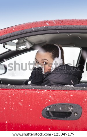 Cute girl with flu symptoms sneezes in a car on snowy  winter day. Using handkerchief closes mouth with her hands.