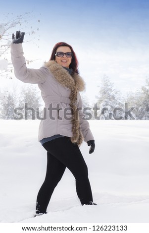 Mid aged cute smiling woman waving hello outdoors on winter day