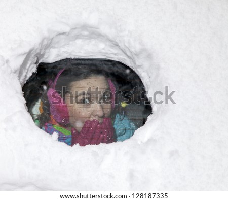 Cute woman driver surprised looking from behind a snowy car window