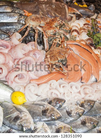 Fresh fishes, crabs, shells, tasty decorated on traditional fish market stand- selective focus on Giltheads