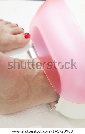 Drying in foot nail enamel drying device, Drying of enamel, series of STEP BY STEP nail varnishing process, HIGH RESOLUTION photos, Closeup, selective focus on nails