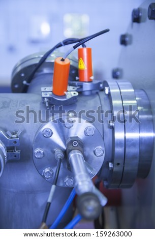 View of Important electronic and mechanical parts of ION Accelerator, with high voltage sign on coils, CNC machined parts,  selective focus  , tilt shift lens, industrial blue toned