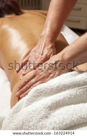 Woman receiving a professional therapeutic massage and lymphatic drainage while lying on a towel in a awarded health massage center,  series of various techniques