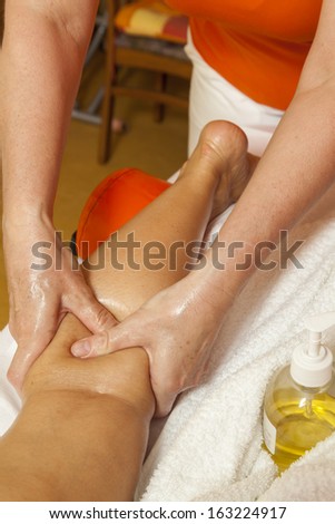 Woman receiving a leg and foot massage and lymphatic drainage while lying on a towel in a awarded health massage center,  series of various techniques