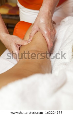 Woman receiving a leg and foot massage and lymphatic drainage while lying on a towel in a awarded health massage center,  series of various techniques
