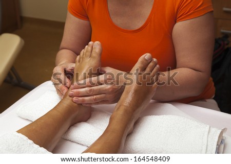 Woman receiving a leg and foot massage while lying on a towel in a awarded health massage center, series of various techniques