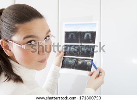 Concerned young woman doctor checking the digital echography photograph of thyroid, ultrasound