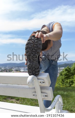 Sporty young woman stretching outdoor on park bench, Close-up, selective focus on on sport shoe sole