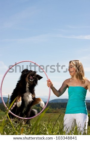 Young woman with dog and tires on a lawn. In the background mountains