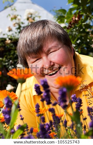 mentally disabled woman is in the garden and smell of flowers