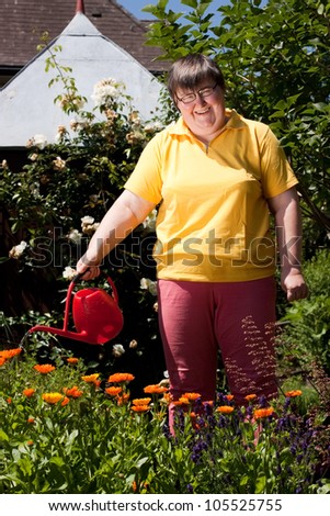 mentally disabled woman stands in the garden and  pours flowers