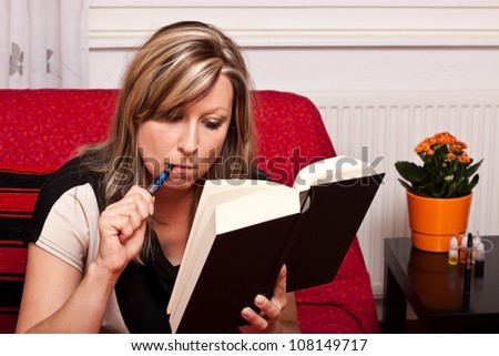 Young blonde woman reading a book, and evaporated to an electric cigarette