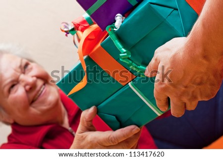 a female Senior sits and gets or give many presents closeup