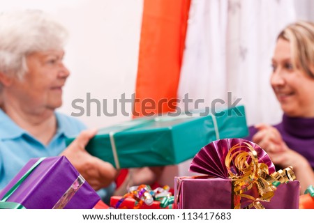 female senior and young women give presents to each other
