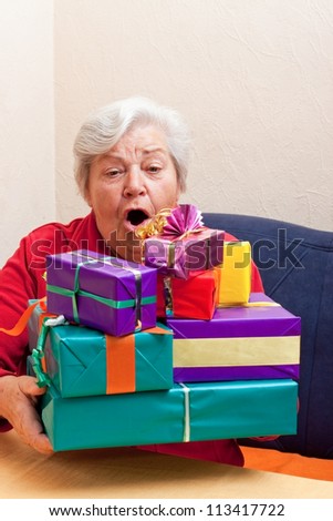 senior sitting on the couch and takes or gives gifts stack
