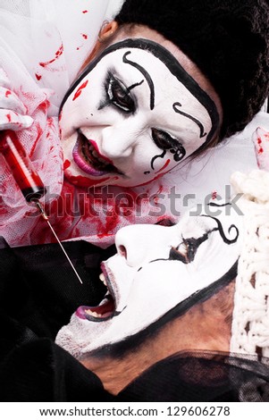 female evil Clown with syringe threatened male clown