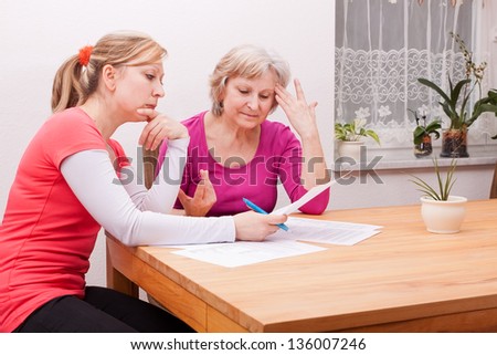 Two women pondering in living room over documents