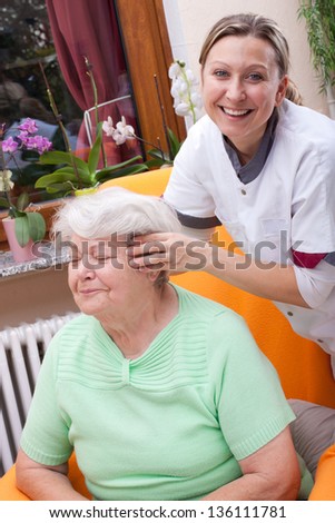 blond Nurse massages the head of a senior