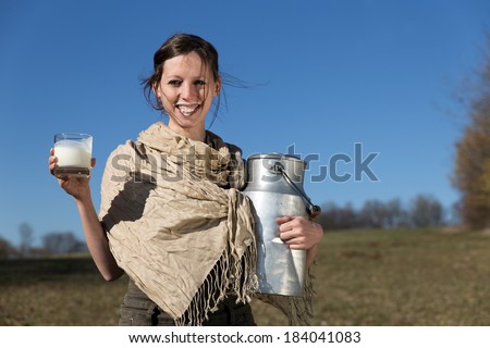 Smiling pretty woman with milk jug and glass full of milk