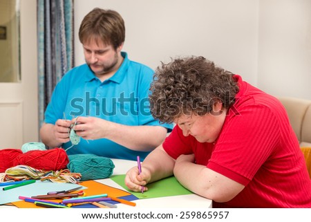 a mentally disabled woman and young man doing arts and crafts